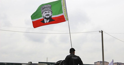 An officer of the Chechen Special Rapid Response Unit (SOBR) with a flag of the Republic with a portrait of Akhmat Kadyrov. May 9, 2015. Grozny. Photo by Magomed Magomedov for the "Caucasian Knot" An officer of the Chechen Special Rapid Response Unit (SOBR) with a flag of the Republic with a portrait of Akhmat Kadyrov. May 9, 2015. Grozny. Photo by Magomed Magomedov for the "Caucasian Knot"