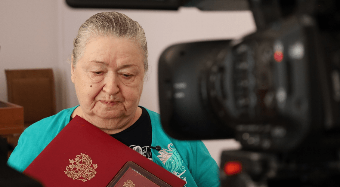 Mother of one of the fighters with her son's award. Screenshot of the photo of the Takhtamukaysky district administration from 20.08.25, https://t.me/tahtamukay/11446.