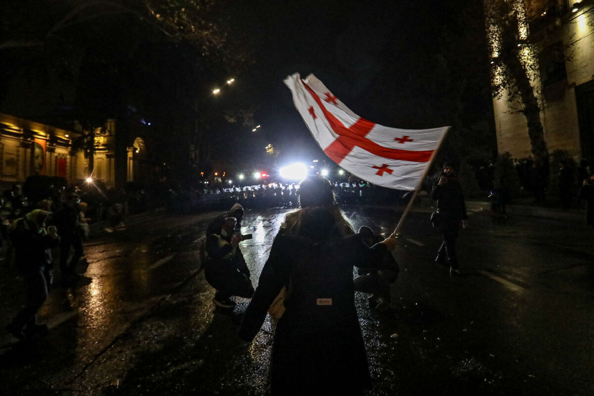 A protester in Tbilisi holds a Georgian flag in front of a police cordon, December 2024. Photo by "Caucasian Knot" correspondent Aziz Karimov.