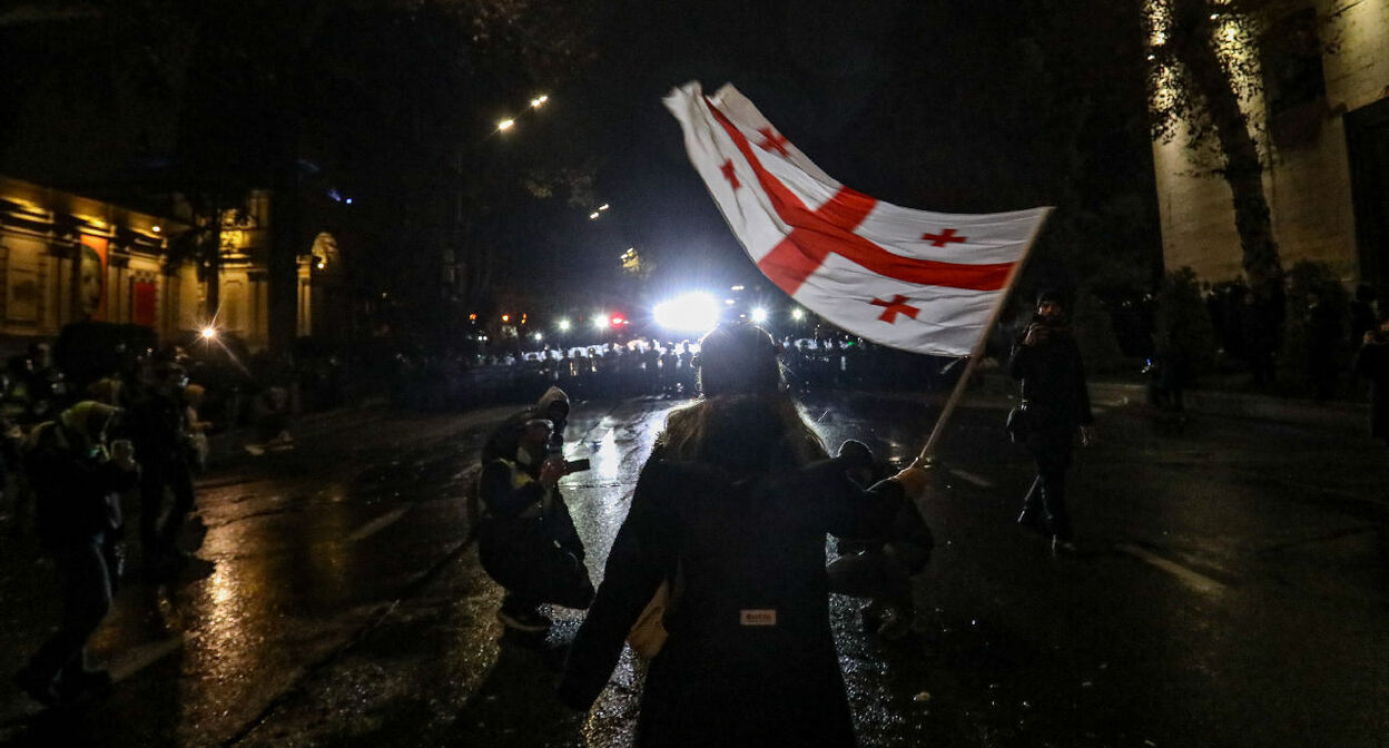 A protester in Tbilisi holds a Georgian flag in front of a police cordon, December 2024. Photo by "Caucasian Knot" correspondent Aziz Karimov.