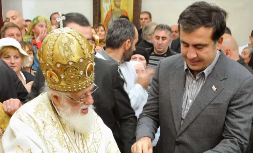 Ilia II and Mikheil Saakashvili. Screenshot from Interpressnews photo from March 19, 2026, https://www.interpressnews.ge/ru/article/173886-mikhail-saakashvili-proshu-dostavit-menia-na-pokhorony-patriarcha-kak-ego-druga-tretego-prezidenta-gruzii Ilia II and Mikheil Saakashvili. Screenshot from Interpressnews photo from March 19, 2026, https://www.interpressnews.ge/ru/article/173886-mikhail-saakashvili-proshu-dostavit-menia-na-pokhorony-patriarcha-kak-ego-druga-tretego-prezidenta-gruzii