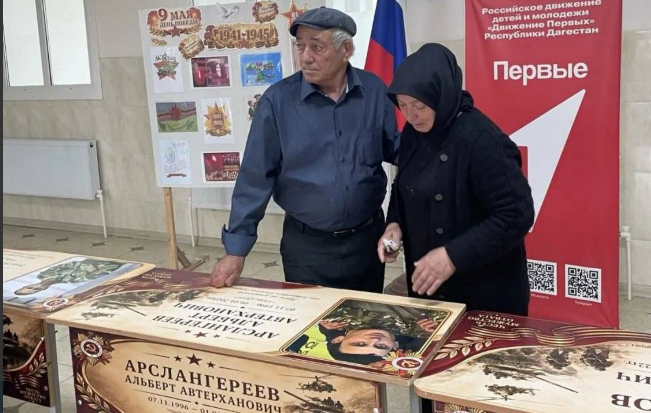 Relatives at the unveiling of a personalized desk. Screenshot from the Babayurt District Administration, May 25, 2026, https://t.me/babayurtrayon/12221?single