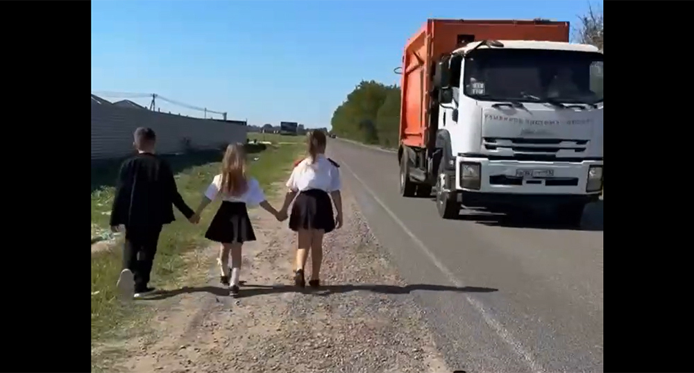 Children walk along the edge of the road due to the lack of a sidewalk. Frame from the video https://t.me/tipichkras/83286